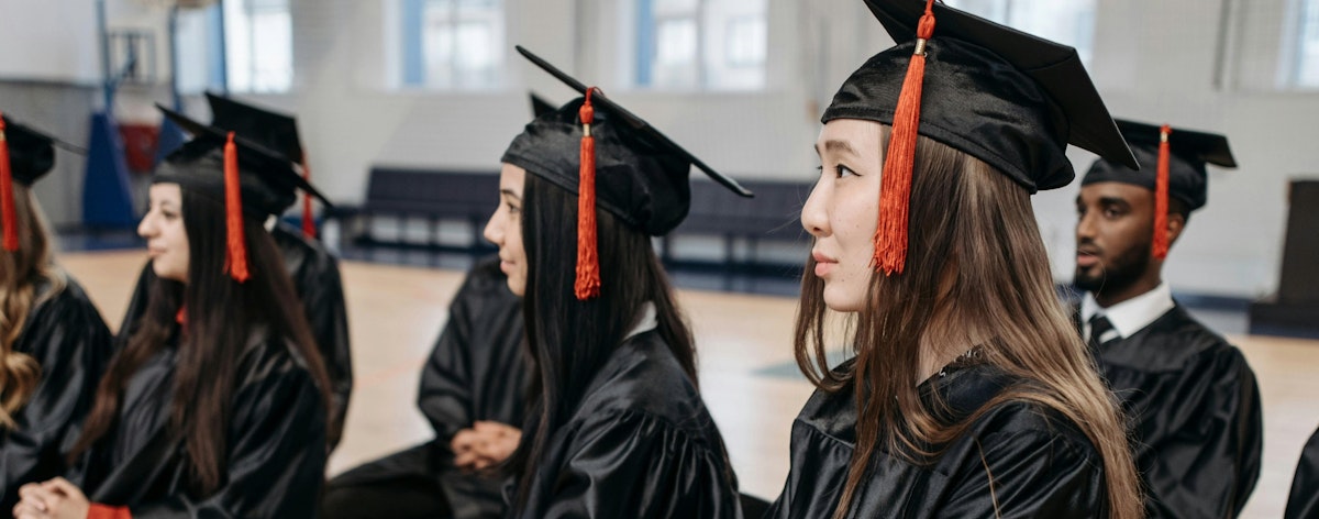 A group of graduates in robes look off to the side.