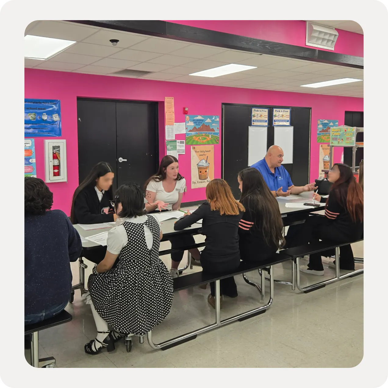 A community partner volunteer talks with students at a Reality Fair table.